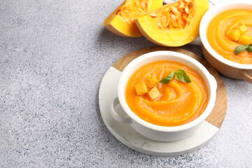 Delicious pumpkin cream soup with basil served on grey table, closeup. Space for text