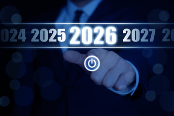 Businessman choosing 2026 year among others from 2024 to 2027 on virtual screen with power symbol against dark background, closeup. New year goals and plans
