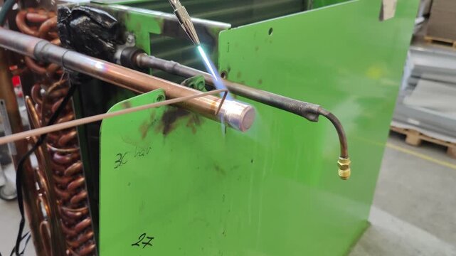 Skilled Technician Brazes Copper Pipes in Industrial Setting