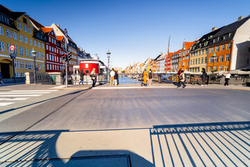 Morning traffic on Copenhagen's famous Nyhavn canal. Tourists stand against backdrop of colorful buildings in Scandinavian city. Life in Danish capital.	
