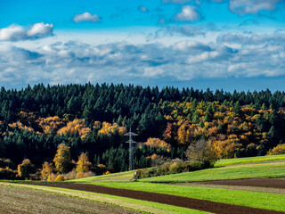 Hochspannungsmasten im herbstlich gefärbtem Mischwald