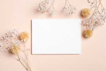 Horizontal white blank card centered on a beige background, styled with dried gypsophila flowers, perfect for elegant wedding invitation mockups