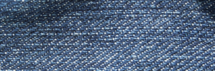Obraz premium Close-up of blue denim fabric texture showing detailed weave pattern in natural light.