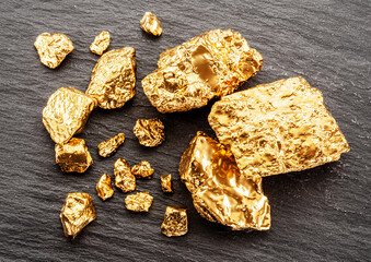 Gold nuggets on black stone background top view. Imitation of gold nuggets.