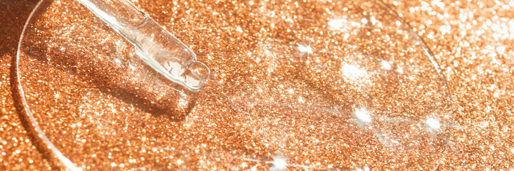 Glittery glass dropper with liquid on shiny gold background for cosmetic or skincare concept.