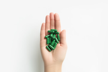Hand Holding Green Capsules on White Background