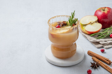 Apple cider with cinnamon, anise, brown sugar and rosemary in a glass on a light background