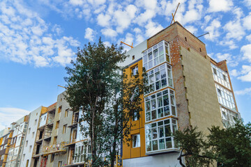 A residential building undergoing extensive reconstruction and repair after wartime damage, showing a mix of unfinished exterior, new balconies, and visible repairs