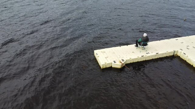 Hombre pescando en un muelle flotante del Lago Ness, Escocia