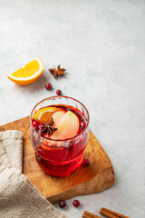 A cranberry drink in a glass on a wooden board on a light background with cinnamon and napkin.