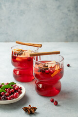 A cranberry drink in a two glasses on a light background with cinnamon and berries. A traditional Christmas punch