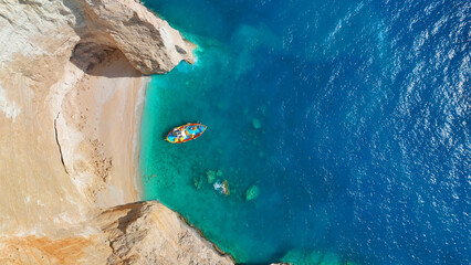 Aerial drone photo of traditional fishing boat anchored in beautiful sea caves with turquoise...