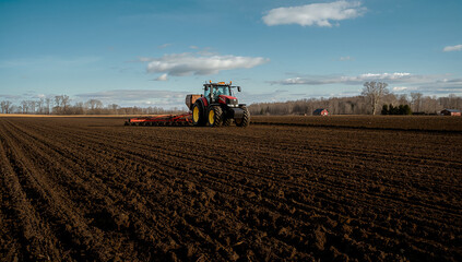 Fototapeta premium Seasonal farm work, a tractor sowing a field in spring, copy space about growing organic crops