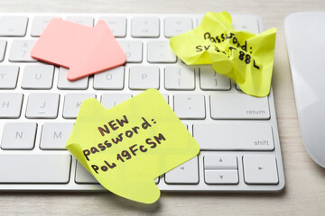 Changing password. Paper notes with new and old passwords, keyboard and computer mouse on light...