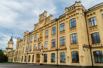 Low-angle view of the large yellow-brick facade of a historic university or technical institution building with decorative masonry and a prominent corner tower