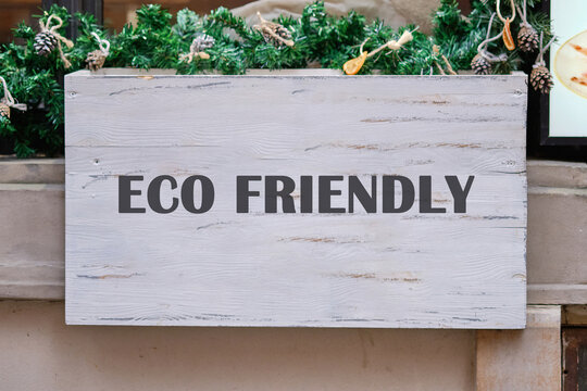 A sign reading eco friendly hangs above a festive display, surrounded by green foliage and rustic decor, showcasing a commitment to sustainability in a lively urban area