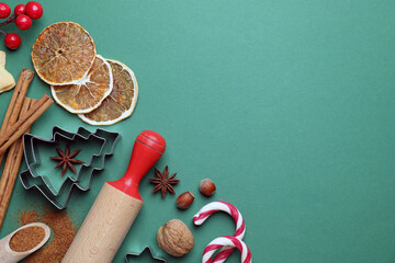 Candy canes, ingredients and utensils for baking cookies on green background, flat lay with space...