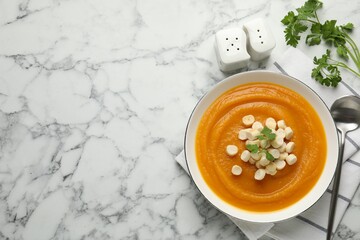 Salt and pepper shakers, pumpkin soup served on white marble table, flat lay. Space for text