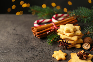 Christmas food. Cookies in shape of stars, spices, candy canes and fir tree branches on grey table against background with blurred lights, space for text. Bokeh effect