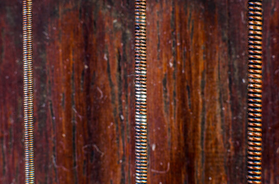 Extreme macro closeup of three copper wrapped strings against wooden background