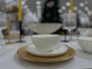  Elegant white tableware on a gold plate for Christmas dinner - Close-up of a festive table setting