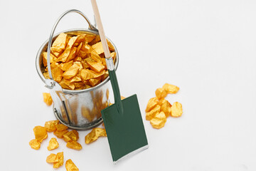 Small metal bucket filled with golden stones on white background. Concept of wealth