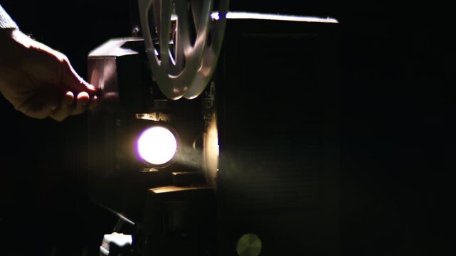 Bright light beam from a vintage film projector turning on in a dark room, with the film reel spinning and projecting light with a cinematic lens flare, representing nostalgia and cinema