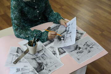 A person is drawing a house with a pencil and ruler