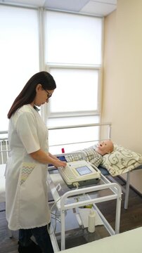 Young medical student practices pediatric ultrasound on a realistic child mannequin in a modern simulation classroom. Vertical video