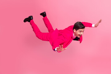 Energetic young man in vibrant pink suit posing stylishly on a bright background, expressing fun...