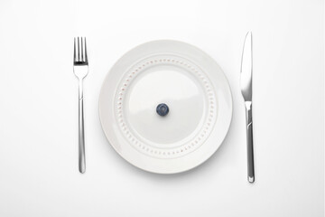 One blueberry on plate and cutlery on white table, flat lay