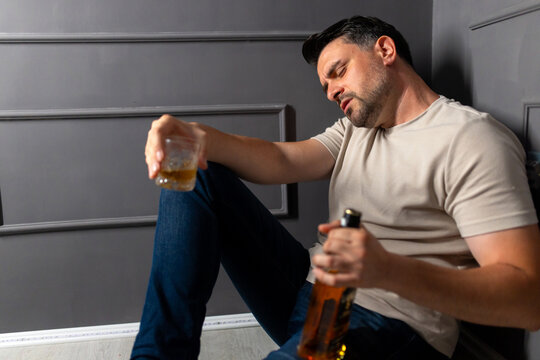A man battles alcohol's effects in a dimly lit space during the evening