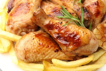 Grilled chicken drumsticks with french fries and spices on plate, closeup