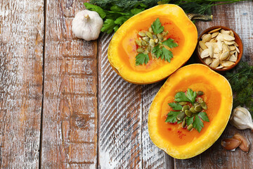 Tasty pumpkin cream soup with seeds, parsley, dill and garlic on color wooden table, flat lay. Space for text
