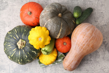 Many fresh pumpkins and other vegetables of gourd family on light grey textured table, flat lay