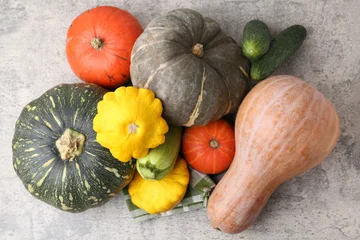 Fototapete Zu Essen Many fresh pumpkins and other vegetables of gourd family on light grey textured table, flat lay  © New Africa