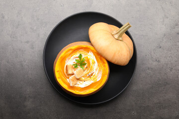 Tasty pumpkin cream soup with croutons and parsley served in pumpkin on grey table, top view