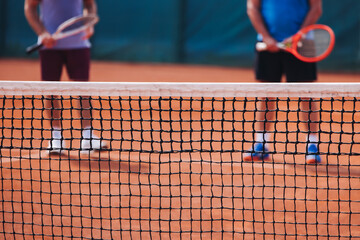 Tennis tournament championship on outdoor clay court with net, professional athletes play in motion with rackets serve tennis ball during tennis match game, tennis training in a sunny day on a stadium