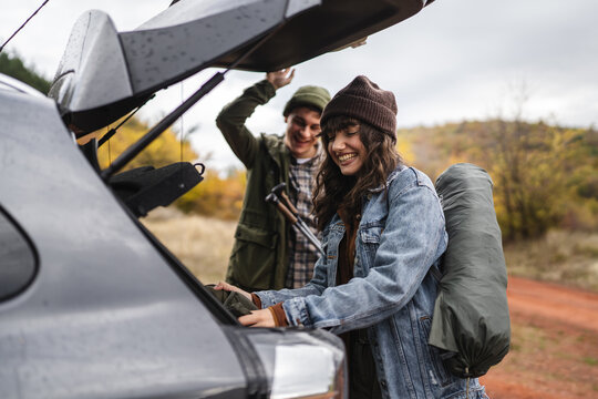 Couple preparing hiking gear from car trunk for fall adventure