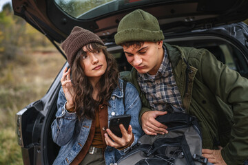 Young couple navigating with smart phone finding direction in nature
