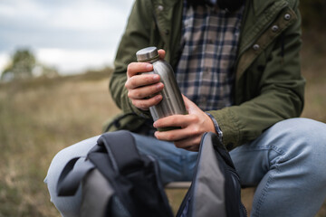 Man holding reusable water bottle during outdoor hike