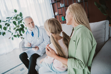 Mom and daughter comforted by a doctor during a family medical visit in a cozy living room setting