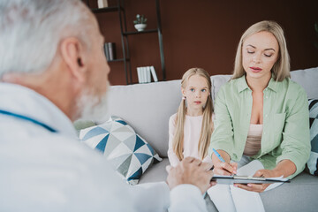 A caring moment with mother and daughter in a cozy living room during a doctor consultation for...