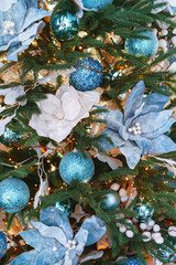 Christmas tree decorated with blue and white floral ornaments with lights and frosted snowy...