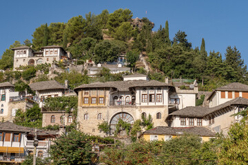 View of stone buildings with green trees in Albania. Hilly Gjirokaster city with its outdoor architecture.