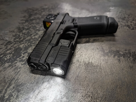 October 23, 2025, Baltics: Close-up of an illuminated original Glock GTL 2 tactical weapon light mounted on a G45 pistol with a red dot sight.
