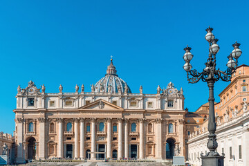 Obraz premium St. Peter's Basilica in Vatican City on Piazza San Pietro with ornate street lamp and clear blue sky. Italian architecture. Travel landmark in Rome city, Italy