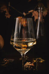 Close-up of white wine glass with golden reflections and soft autumn tones in moody background