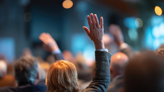 Several people raise hands in a conference setting.