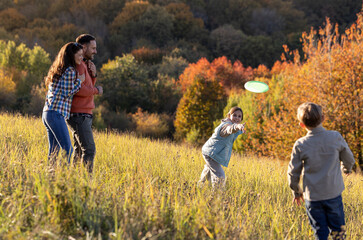 Family playing frisbee in a sunny field during afternoon